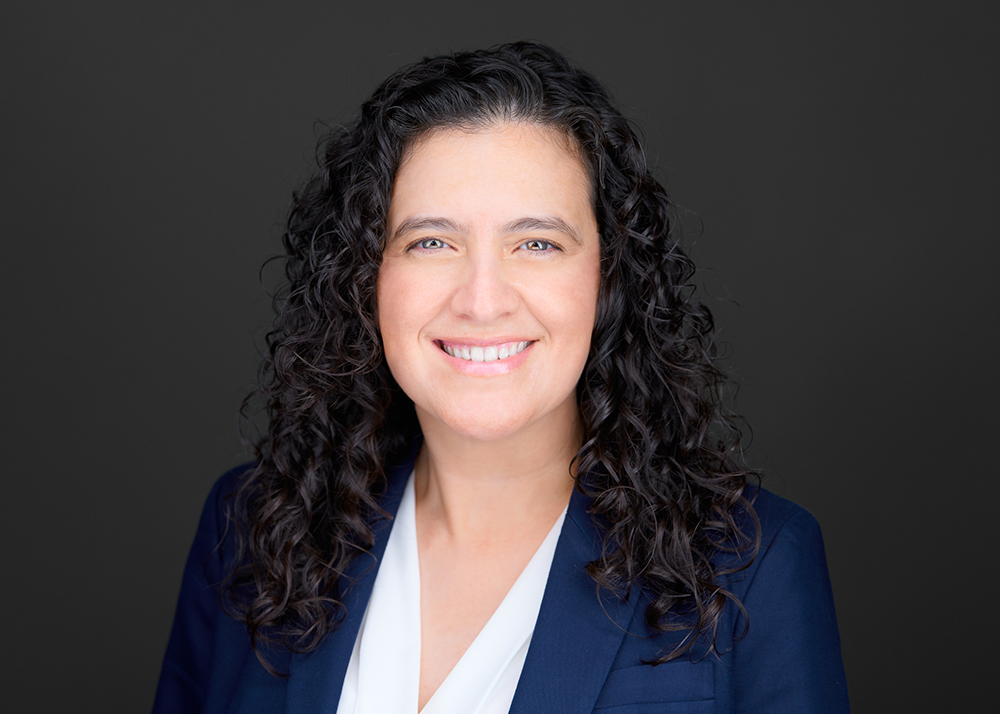Perla Gámez smiles in front of a dark background